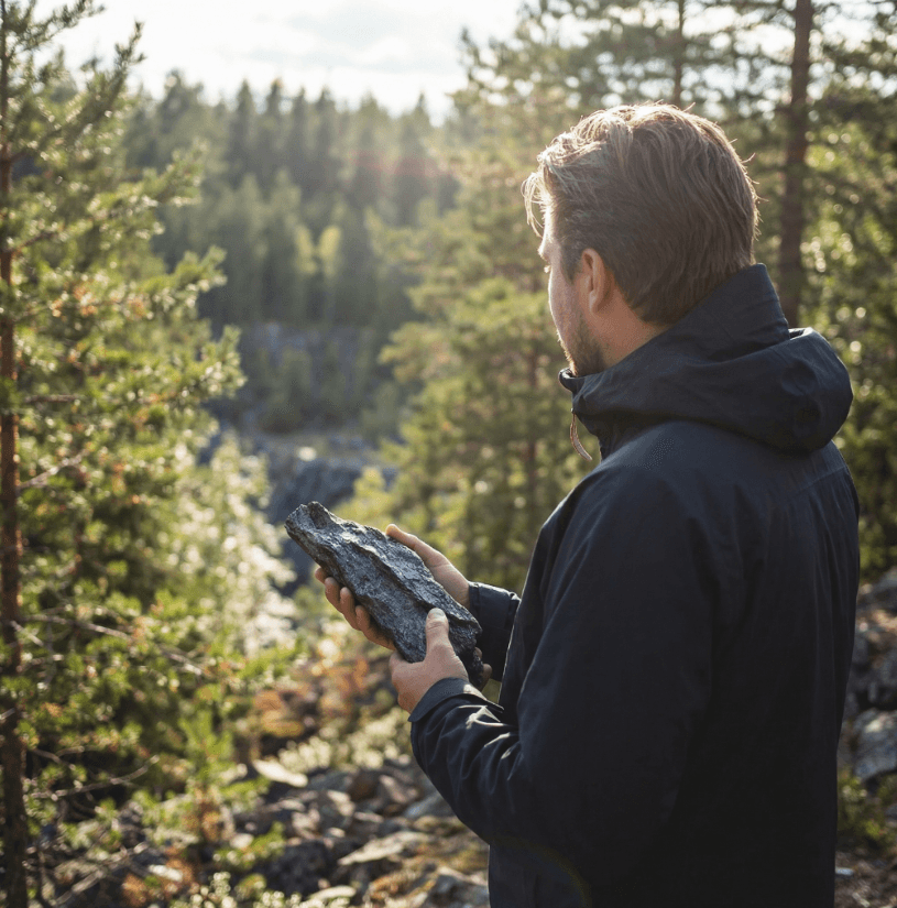 Victor Blom in a forest landscape holding a mineral sample